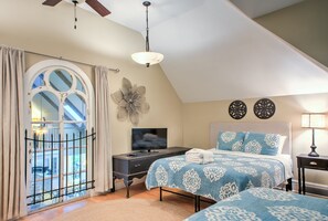 A bedroom with a bed, a TV, a desk, and a window with curtains.