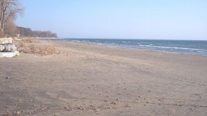 Ein Strand mit klarem Himmel, einem Felsen und dem Meer.