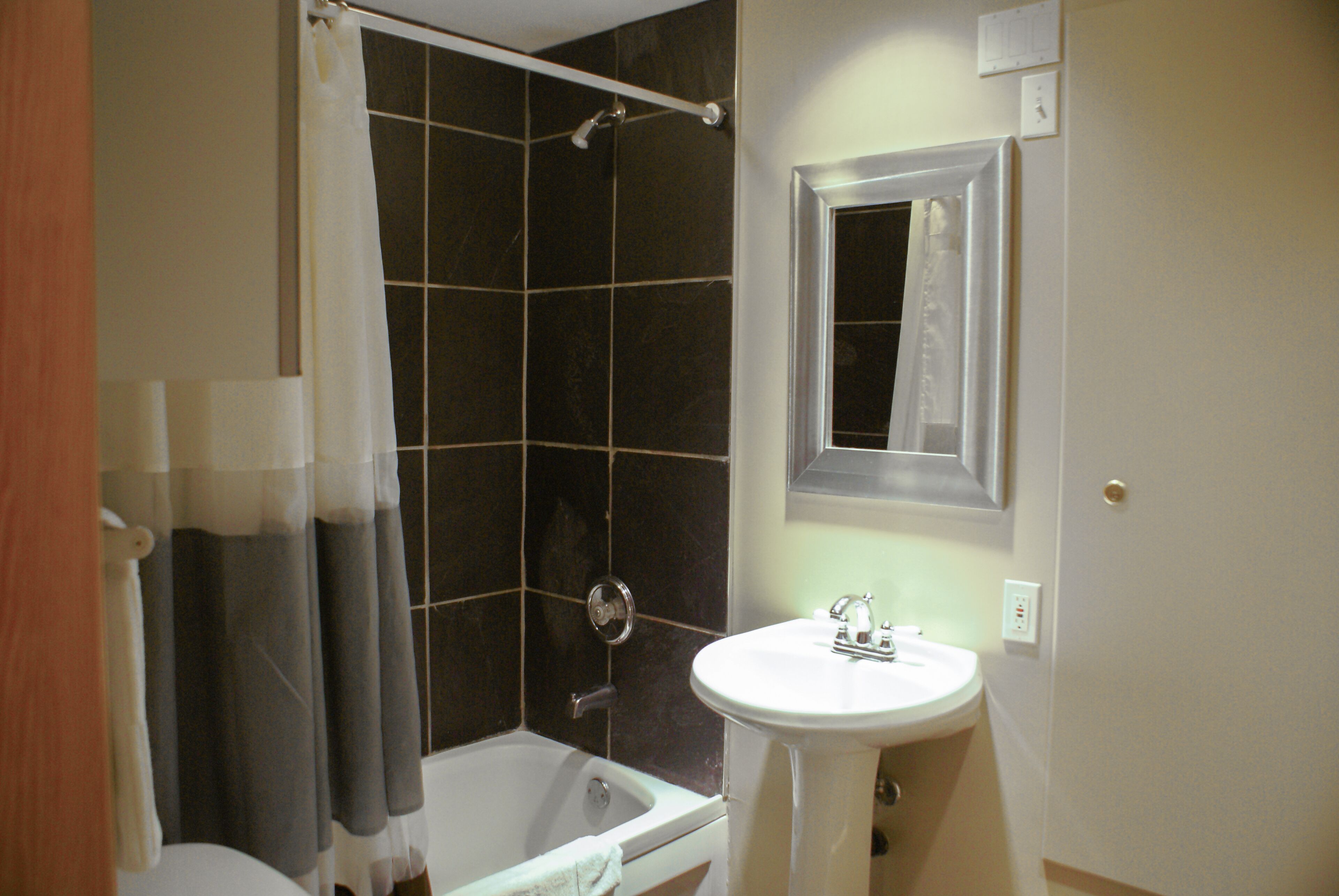 A bathroom with a bathtub, a shower, a sink, and a mirror.