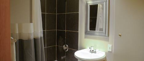 A bathroom with a bathtub, a shower, a sink, and a mirror.