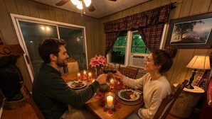 Ein Esszimmer mit Holztisch, Stühlen, Kerzen und einem gerahmten Bild an der Wand.