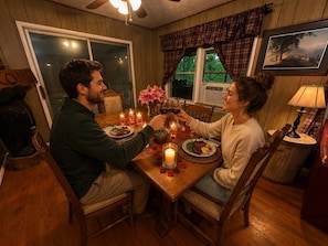 Une salle à manger avec une table en bois, des chaises, des bougies et un tableau encadré au mur.
