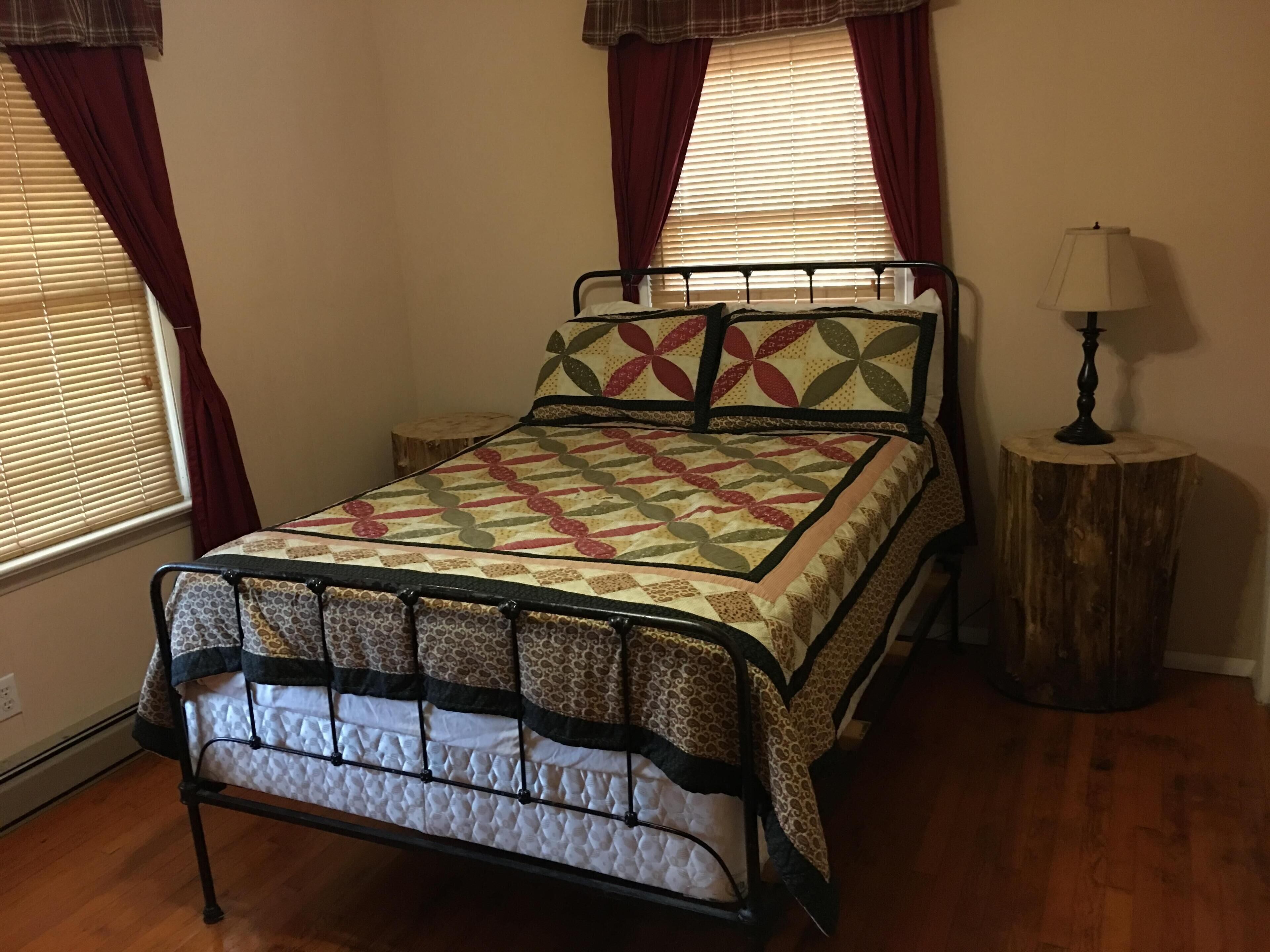 A bedroom with a bed, a nightstand, a lamp, and a window with curtains.