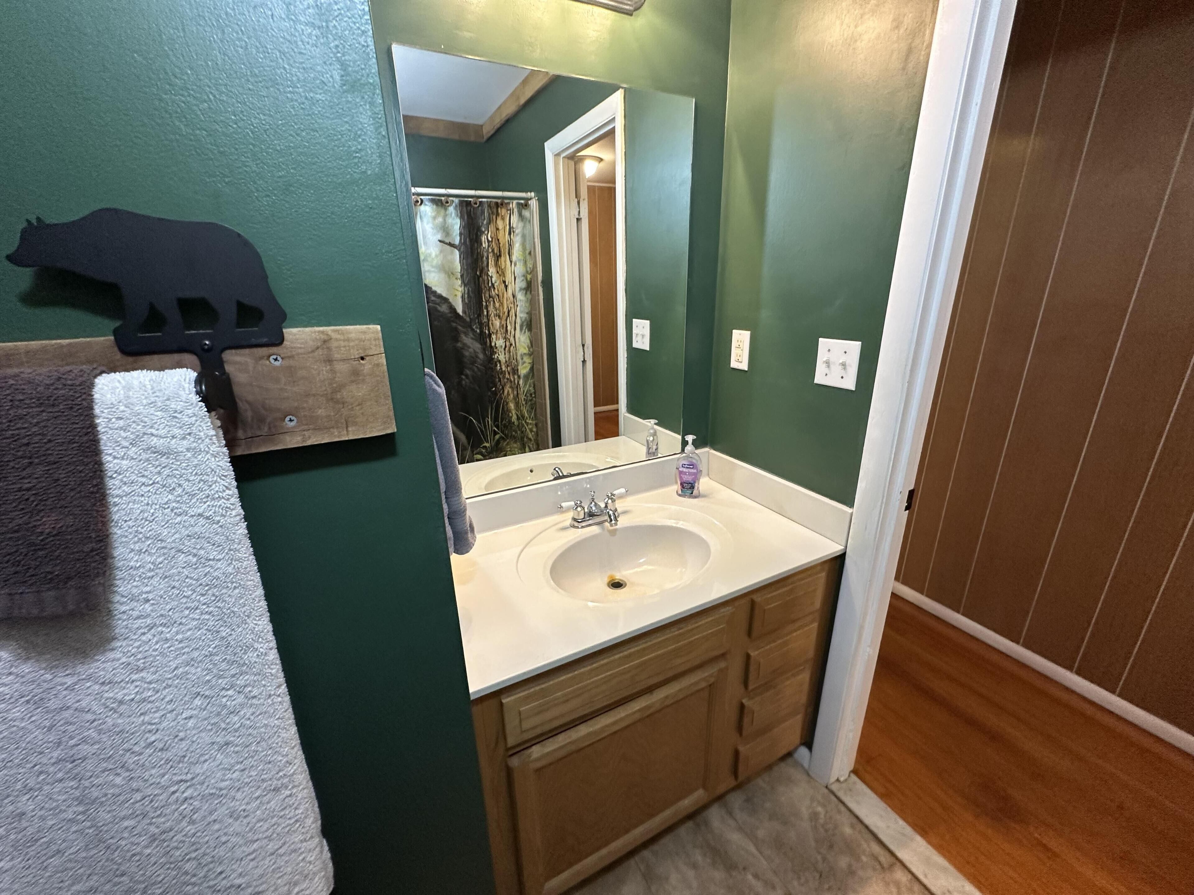 A bathroom with a sink, mirror, towel rack, and wooden cabinets.