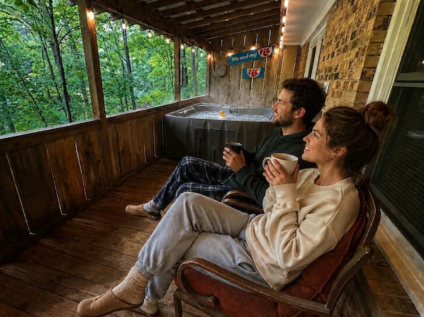 Une terrasse en bois offrant une vue sur les arbres, un jacuzzi et une pancarte sur laquelle on peut lire : « Moi et ma voiture télécommandée ».