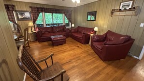 Ein Wohnzimmer mit Holzboden, Deckenventilator, Kamin und einem Essbereich mit Tisch und Stühlen.