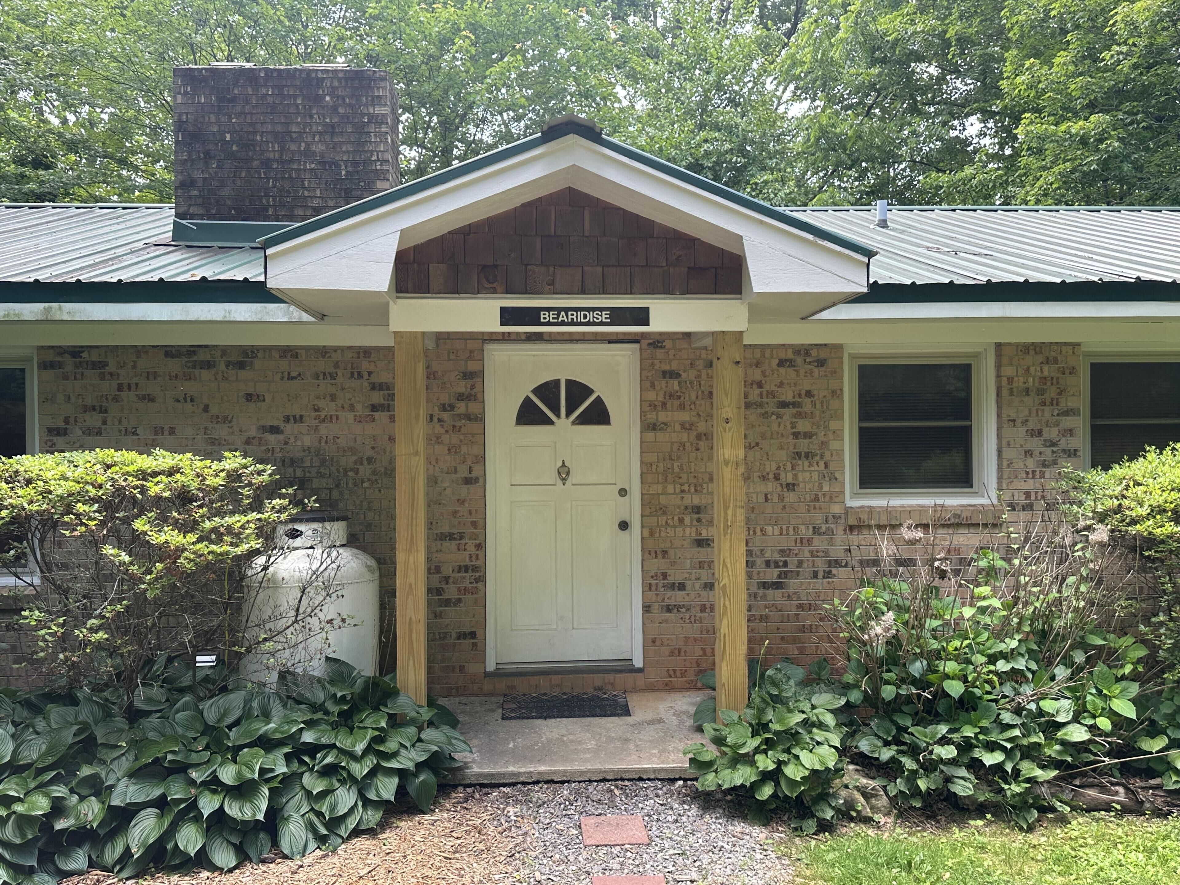 A brick building with a white door, a small porch, and a sign that reads 'BEARIDISE.'