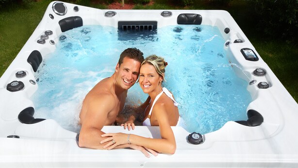Ein Whirlpool mit mehreren Düsen, einer Bedienkonsole und einer Person sowie einem Kind darin.
