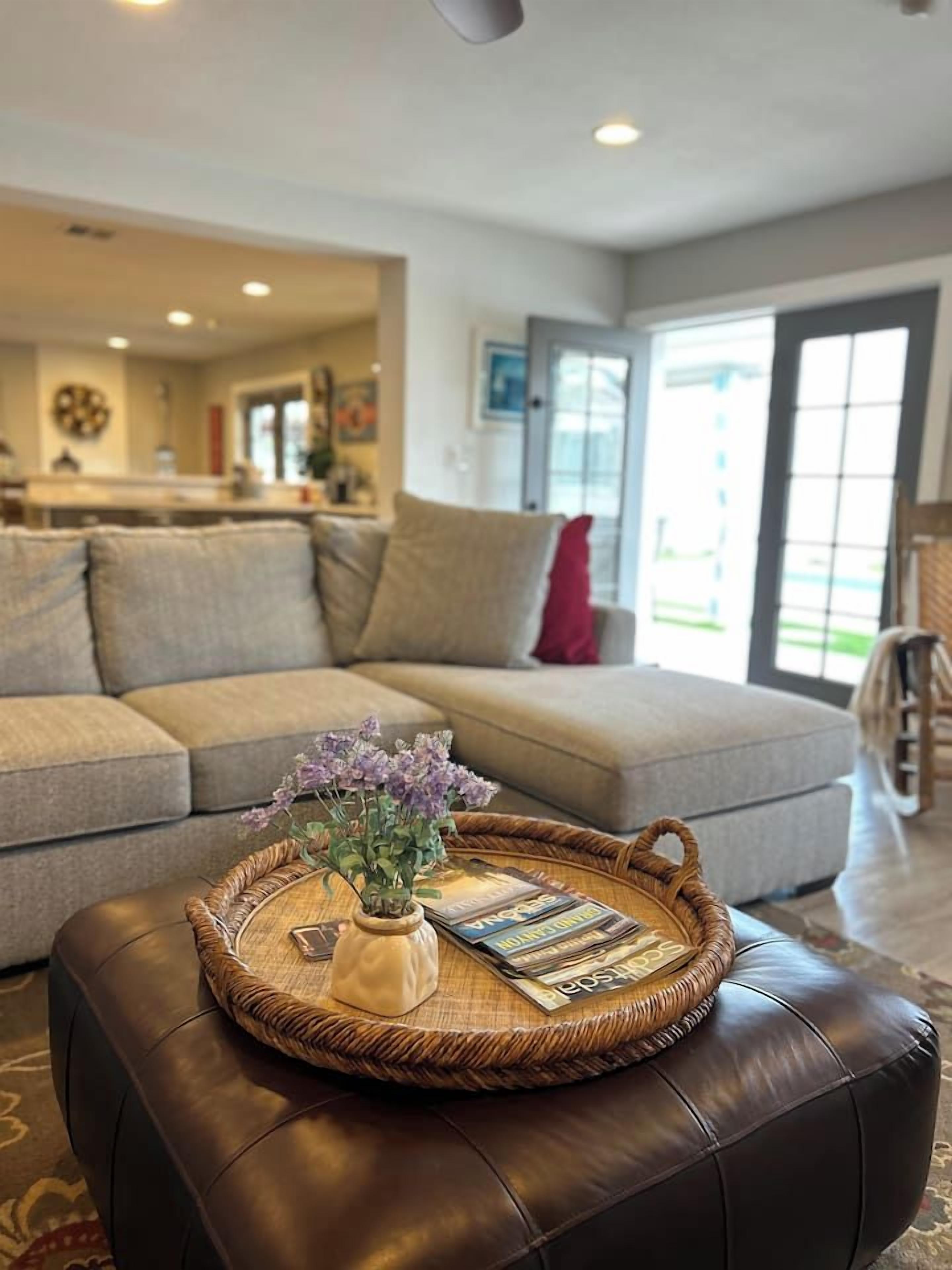 A living room with a sofa, a coffee table with a tray, and a dog.