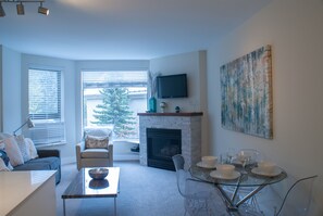 A living room with a fireplace, a television, a dining table with chairs, and a couch.