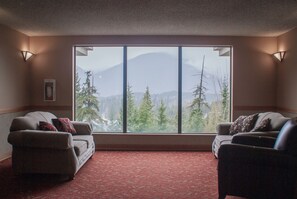 A room with two sofas facing a large window with a mountain view.