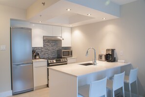 A modern kitchen with a stainless steel refrigerator, a built-in microwave, a stove, and a coffee maker.