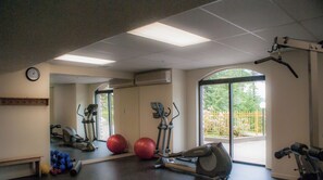 A gym with exercise equipment, a clock, and a large window.