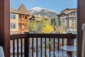 Une vue sur la montagne depuis un balcon doté de balustrades en bois, une table de billard et un panneau indiquant « Tues Roles ».