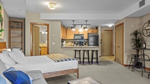 Et lille hotelværelse med seng, sofa, tekøkken og spisebord.