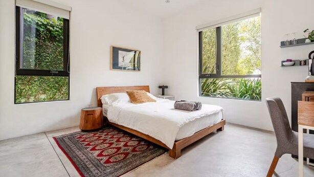 A bedroom with a bed, a nightstand, a chair, and large windows. - Contemporary suite in Santa Monica with private entrance (Santa Monica)