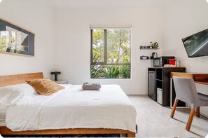 A bedroom with a bed, a desk, a chair, a television, a window with a view of trees, and a framed picture on the wall. - Contemporary suite in Santa Monica with private entrance (Santa Monica)
