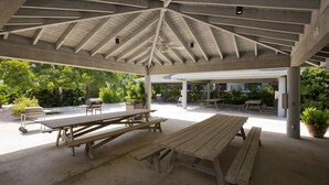 An outdoor covered picnic area with multiple wooden picnic tables and a grill. - Vibrant Island retreat, Expansive private balcony, Enjoy  the Coastal Breezes (Key West)