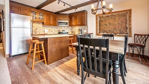 A kitchen with wooden cabinets, a stainless steel refrigerator, a microwave, and a large island with stools. - 2 Bed / 2 Bath With Amazing Views Steps From Gondola (Vail)