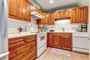 A kitchen with wooden cabinets, white appliances, and a tiled backsplash.