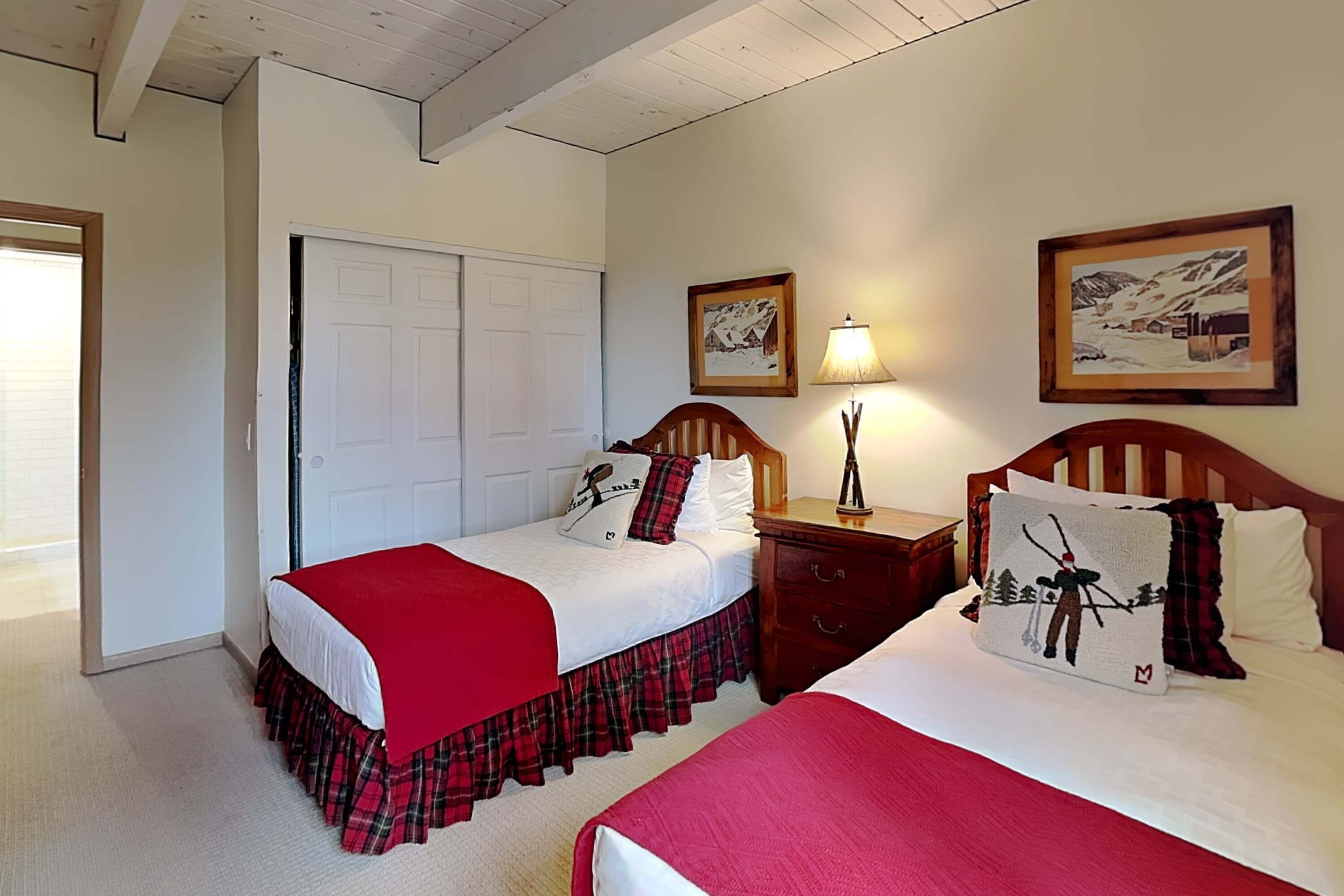 A bedroom with two beds, a wooden headboard, a nightstand, a lamp, and two framed pictures on the wall.