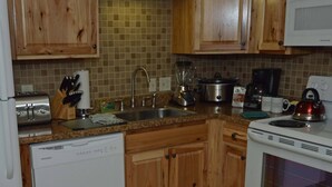 Una cucina con pensili in legno, lavello in acciaio inossidabile, un tostapane, un frullatore, un bollitore e una macchina per il caffè.
