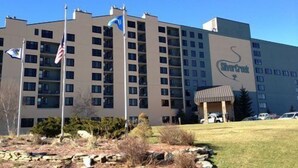 Un hotel a più piani con un cartello ben visibile 'Silver Creek', numerosi balconi e un piccolo parcheggio con auto.