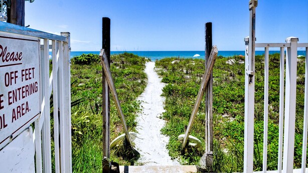 Un sendero que conduce a una playa, con un letrero que dice 'Prohibido el paso a pie'.
