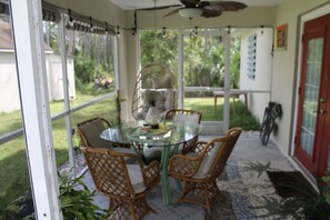 A glass-enclosed patio with wicker chairs, a glass table, and a ceiling fan. - 3 Bedroom home with a Key West Feel (North Port)