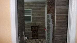 Un baño con suelo de baldosas, un cajón de madera y un perchero.
