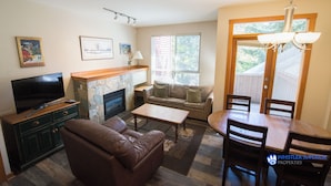 A living room with a fireplace, a television, a sofa, a coffee table, and a dining table with chairs.