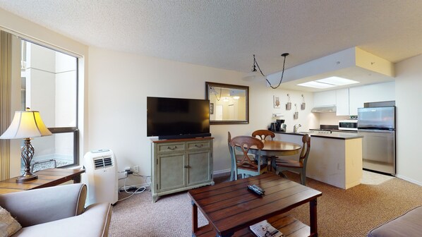 A compact living space with a flat-screen TV, a dining table, a sofa, and a kitchenette area. - Marquise on Blackcomb, Pool & Hot Tub, Easy Ski Access, Free WiFi (Whistler)