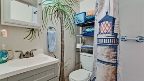 Une salle de bain avec un lavabo blanc, un miroir, un porte-serviettes, des toilettes et un rideau de douche à motifs géométriques.