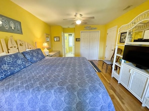 Quarto com cama grande, ventilador de teto, televisão e guarda-roupa.