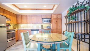 A kitchen with wooden cabinets, a glass dining table, and chairs.