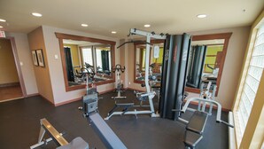 Een sportschool met diverse trainingsapparaten, spiegels en een zwarte bokszak.