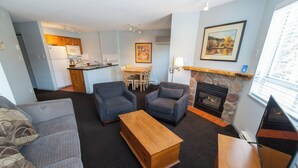 Een knus woongedeelte met een kitchenette, een eethoek, een open haard en een bank.