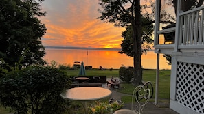 Un patio con mesa y sillas, con vista a un lago al atardecer.
