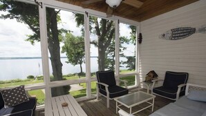 A covered outdoor seating area with a view of a lake, furnished with chairs and a table. - Lakefront Home in the Heart of Aurora, Sunset Ready! (Aurora)