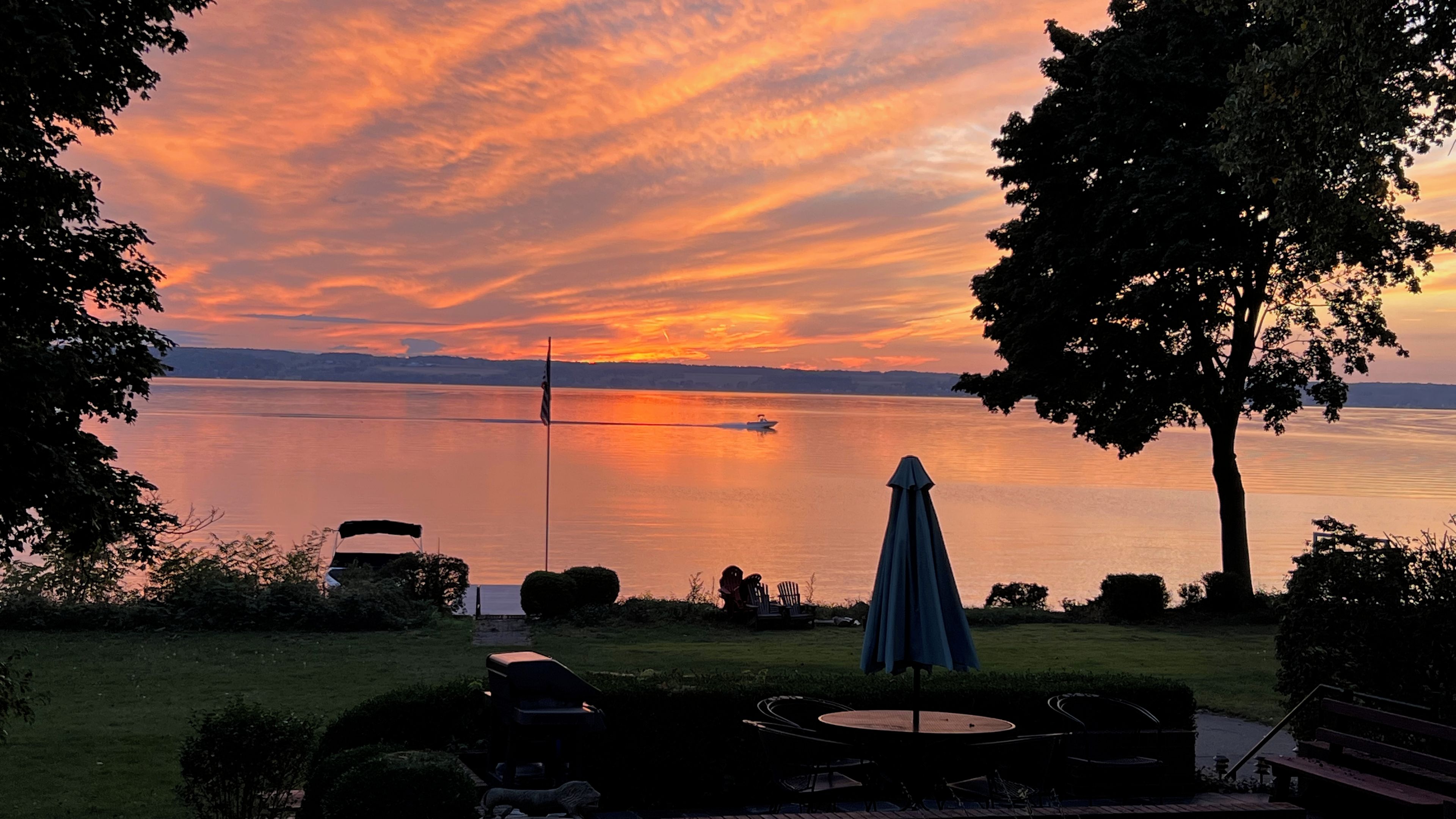 Une vue sur le lac avec un bateau, un drapeau et des sièges à l’extérieur.