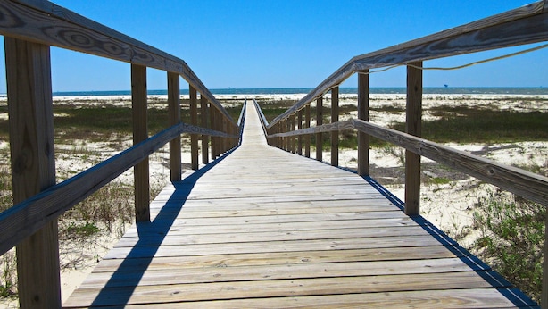 Ein hölzerner Steg führt zum Strand.