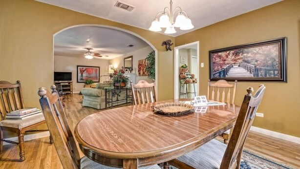 A dining area with a wooden table and chairs, a chandelier, and a painting on the wall. - A perfect home for your vacation! (Waco)