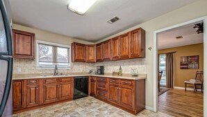 A spacious kitchen with wooden cabinets, a dishwasher, and a large island. - A perfect home for your vacation! (Waco)