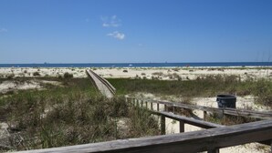 A beach with a wooden boardwalk leading to the shore, sandy dunes, and a clear blue sky. - The Inn at Dauphin Island 106 1BR Walks right out to Pools and Beach! (Dauphin Island)