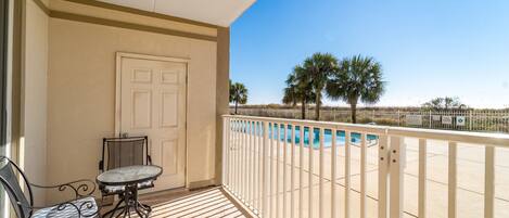 A balcony with a pool view, a door, and a table with chairs.