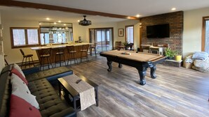 Un salon spacieux équipé d’une table de billard, d’un coin bar et d’une cheminée.