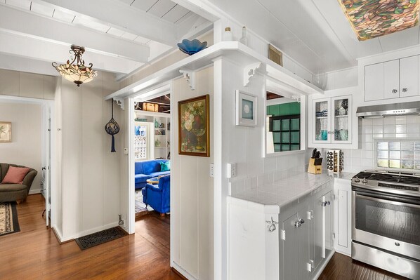A kitchen with white cabinetry, a stainless steel stove, and a window with a view.