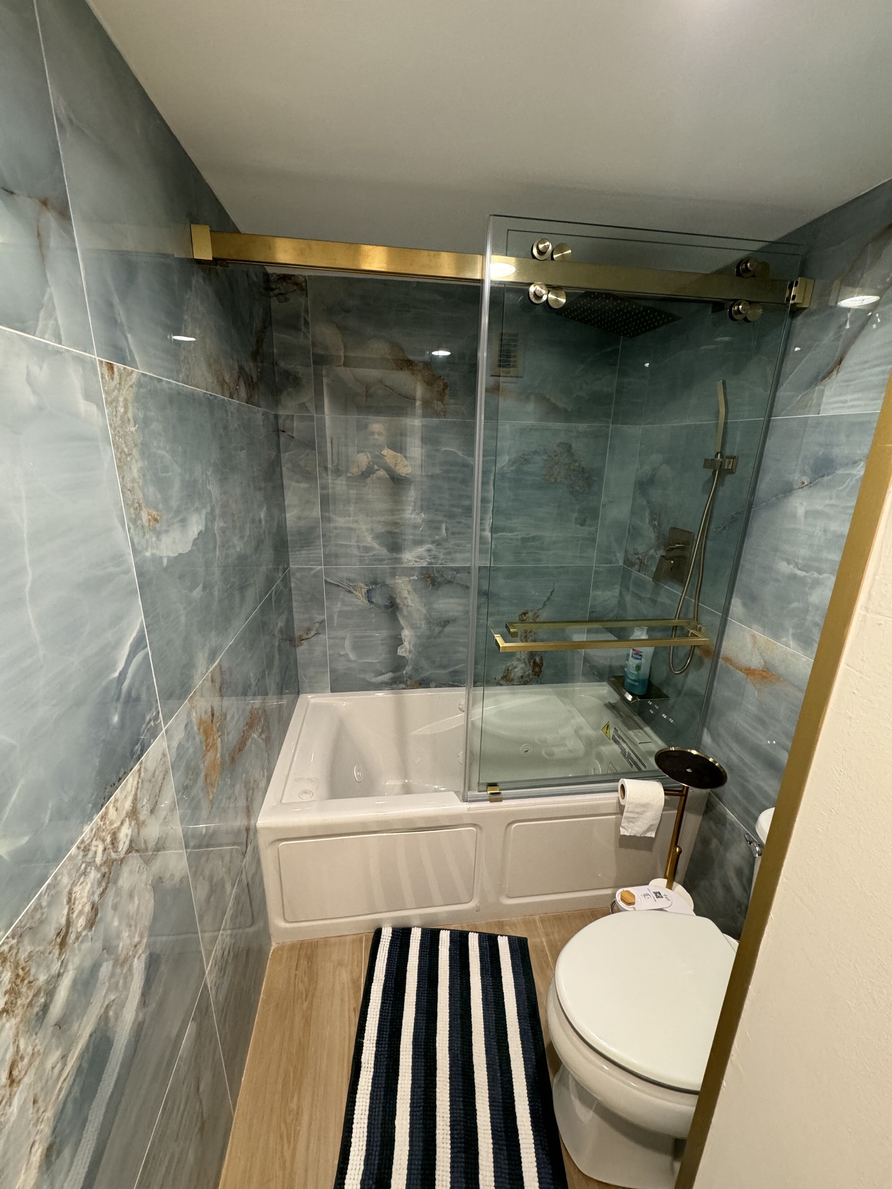 Un baño con ducha acristalada, bañera blanca y un inodoro.