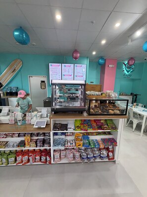 Un caffè con una bacheca dei menù, una vetrina e scaffali pieni di snack e bevande.