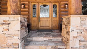A wooden log cabin entrance with a stone staircase and two lanterns. - Deer Valley Cabin W/ Hot Tub | Theater (Park City)